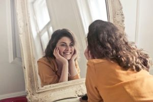 Girl smiling into mirror after final visit to cosmetic dentists in Glasgow city centre